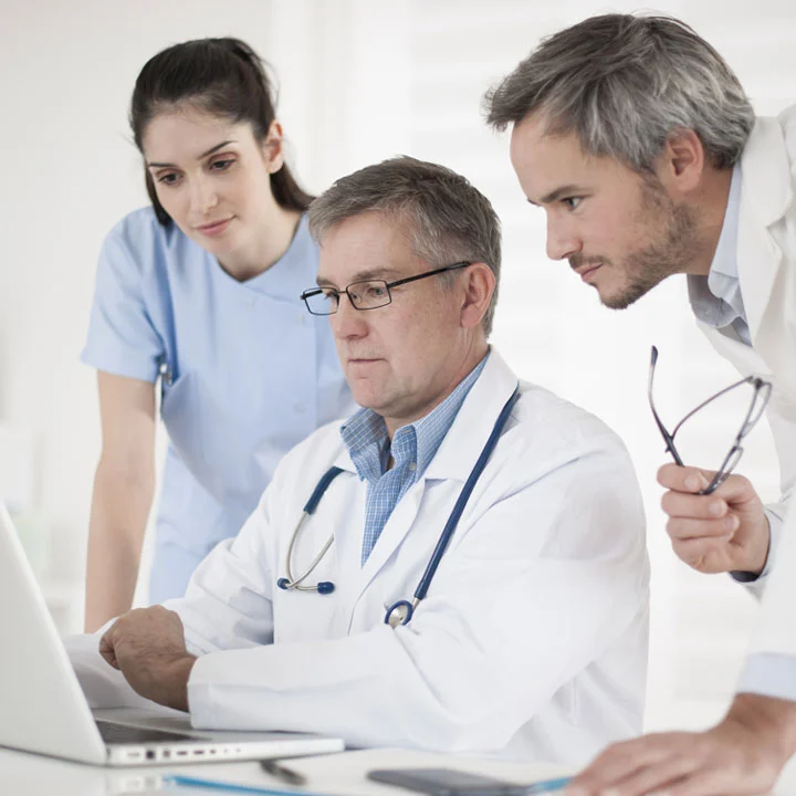 Image of three people in scrubs looking at a computer screen